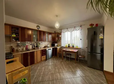a kitchen with wooden cabinets and a table and a refrigerator at Zielony Gaj in Gaj