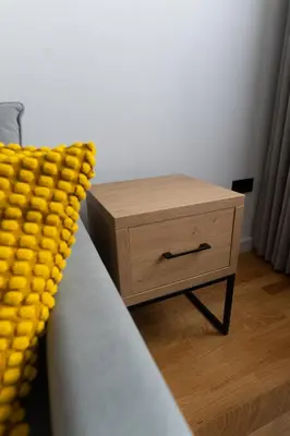 a bed with a yellow blanket next to a night stand at Apartamenty Loftove in Wadowice