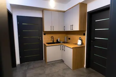 a kitchen with white cabinets and black doors at Apartamenty Loftove in Wadowice