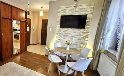a living room with a table and chairs and a television at Modern Apartment SANDY BEACH down town, aquapark, free parking in Kraków