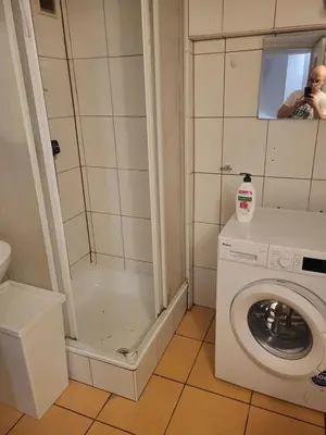 a man taking a picture of a bathroom with a washing machine at Grzegorzecka Room nr 2 in Kraków