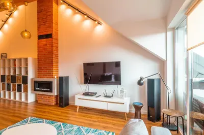 a living room with a large tv on a wall at Modlnica Wierzbowa Cosy Apartment by BookingHost in Kraków