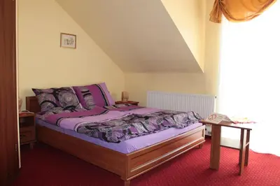 a bedroom with a bed with purple sheets and a table at Zajazd Skorpion B&B in Oświęcim