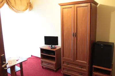 a bedroom with a television and a wooden cabinet at Zajazd Skorpion B&B in Oświęcim