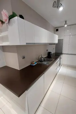 a kitchen with white cabinets and a black counter top at Masarska Family Apartment free Parking in Kraków