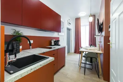 a kitchen with red cabinets and a sink and a table at Zabłocie Residence in Kraków