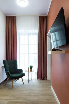 a living room with a green chair and a window at Zabłocie Residence in Kraków