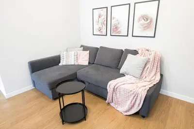 a living room with a gray couch and a stool at Nowoczesny Apartament Dąbska Arena / Parking in Kraków