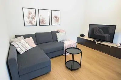 a living room with a blue couch and a tv at Nowoczesny Apartament Dąbska Arena / Parking in Kraków