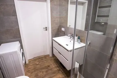 a bathroom with a white sink and a shower at Nowoczesny Apartament Dąbska Arena / Parking in Kraków