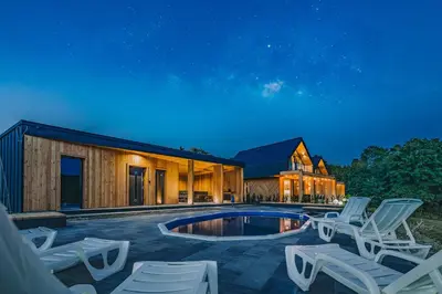 a house with a pool and lounge chairs at night at Słone Wzgórze in Rabka