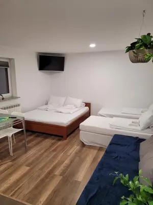 a room with two beds and a tv on the wall at Apartamenty Kącik 8 in Kraków