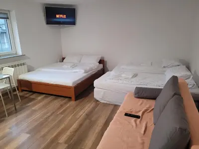 two beds in a room with a couch and a tv at Apartamenty Kącik 8 in Kraków