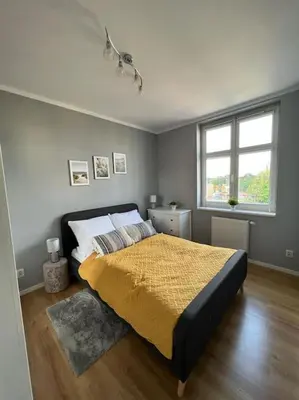 a bedroom with a bed with a yellow blanket and a window at Walenty Kraków in Kraków