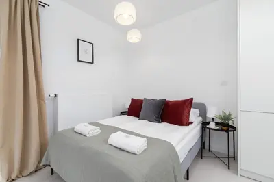 a white bedroom with a bed with red pillows at Modern Studio & Terrace Kiełkowskiego by Noclegi Renters in Kraków