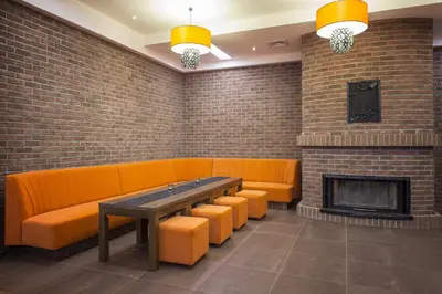 a restaurant with orange couches and a fireplace at Dworek nad Rozlewiskiem in Olkusz