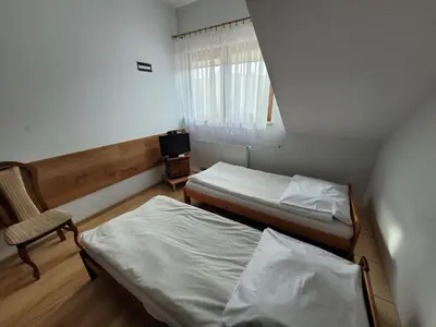 a small bedroom with two beds and a chair at Złota Róża in Sędziszów
