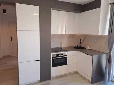 a white kitchen with white cabinets and a sink at Limanowa Sunriser Apartment in Limanowa