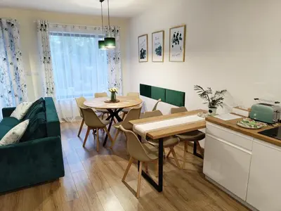 a kitchen and living room with a table and a couch at Domek Zielone Marzenie in Chrzanów