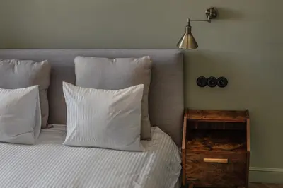a bed with white pillows and a lamp and a night stand at Królewska Deluxe Comfy Apartment by BookingHost in Kraków