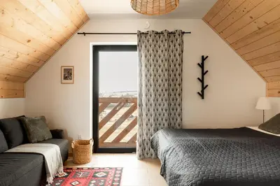 a bedroom with a bed and a couch and a window at Szczyt Beztroski- Domki Wellness Balia & Sauna in Nowy Targ