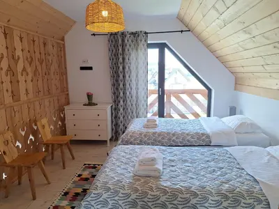 a bedroom with two beds and a window at Szczyt Beztroski- Domki Wellness Balia & Sauna in Nowy Targ