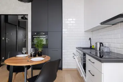 a kitchen with a wooden table and black cabinets at Kraków Studio with Parking & Terrace near Zalew Bagry by Renters Prestige in Kraków