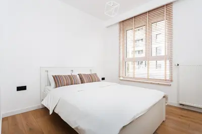 a white bedroom with a large white bed and a window at City of the Kings-Julia Apartment in Kraków