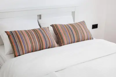 a white bed with two striped pillows on it at City of the Kings-Julia Apartment in Kraków