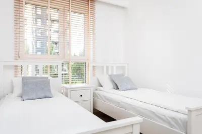 two beds in a white room with windows at City of the Kings-Julia Apartment in Kraków