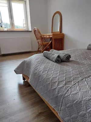 a bedroom with a bed and a chair and windows at Agroturystyka ,Jarzębina' in Harkabuz