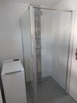 a shower with a glass door next to a refrigerator at Agroturystyka ,Jarzębina' in Harkabuz