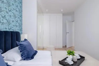 a bedroom with a bed with blue pillows and a table at Vetulaniego Apartment with Air Conditioning & Parking by Renters Prestige in Kraków