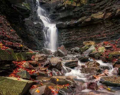 a waterfall on the side of a mountain with rocks at Zawoja u Zbója in Zawoja