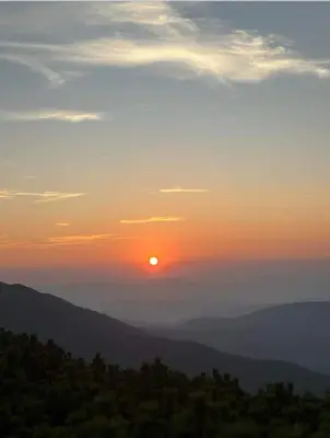 a sunset with the sun setting over the mountains at Zawoja u Zbója in Zawoja