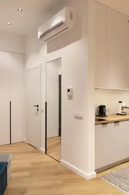 a living room with white walls and a kitchen at Modern Apartment with Air Conditioning, Old Town & Vistula River in Kraków