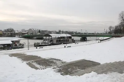 a snow covered river with a bridge in the background at Modern Apartment with Air Conditioning, Old Town & Vistula River in Kraków