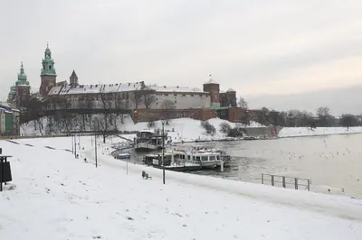 a snowy city with boats docked on a river at Modern Apartment with Air Conditioning, Old Town & Vistula River in Kraków