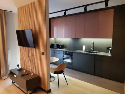 a kitchen with brown cabinets and a chair and a table at Apollo Apartments Masarska 6 in Kraków