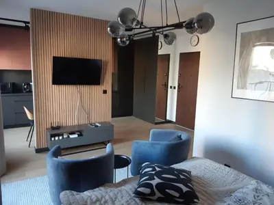 a living room with a bed and two blue chairs at Apollo Apartments Masarska 6 in Kraków