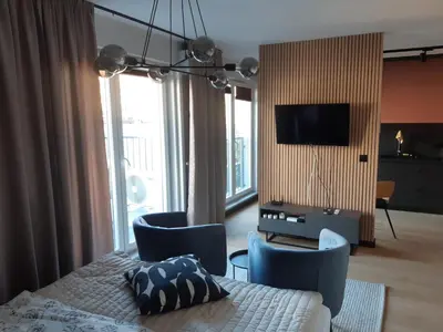 a bedroom with a bed and chairs and a television at Apollo Apartments Masarska 6 in Kraków