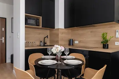 a kitchen with a table and chairs and a kitchen with black cabinets at Beautiful Steam Park Apartment with Parking Old Town Cracow by Noclegi Renters in Kraków