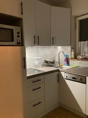 a kitchen with white cabinets and a sink and a microwave at Old Town Sky Apartment in Kraków