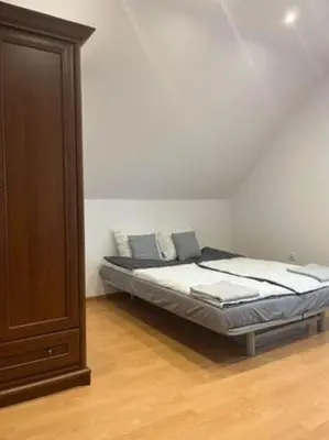 a bedroom with a bed and a wooden cabinet at Noclegi Wilga in Gromiec
