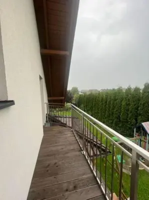 a balcony with a wooden walkway next to a building at Noclegi Wilga in Gromiec