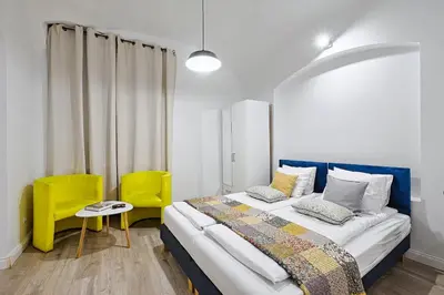 a bedroom with a bed and two yellow chairs at Urban Nest Apartments Szewska 21-R in Kraków