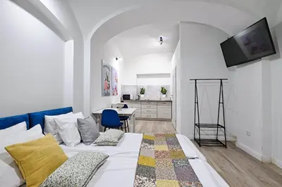 a bedroom with a bed and a desk and a tv at Urban Nest Apartments Szewska 21-R in Kraków