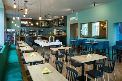 a restaurant with wooden tables and blue chairs at Happy Tower in Kraków