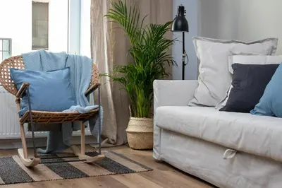 a wicker chair sitting next to a couch with pillows at Barbacan Suites - Old Town Apartments - by Upstairs in Kraków
