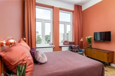 a bedroom with a bed and a tv and windows at Barbacan Suites - Old Town Apartments - by Upstairs in Kraków
